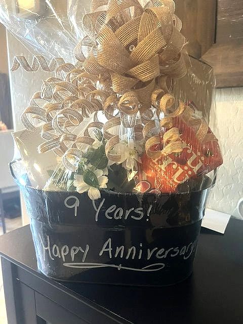 Chalkboard bucket reading '9 Years! Happy Anniversary' filled with treats and topped with gold curly ribbon
