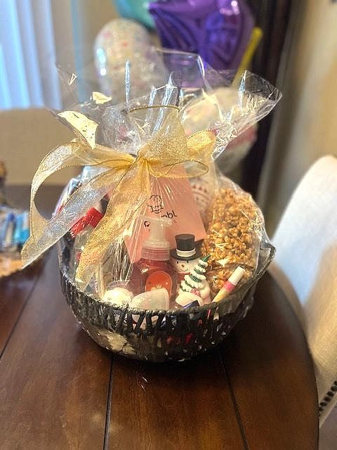 Birthday basket with treats, wrapped in cellophane with a gold ribbon bow