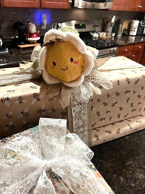 Presents in bee-print paper with a smiling flower plush and a sheer white bow