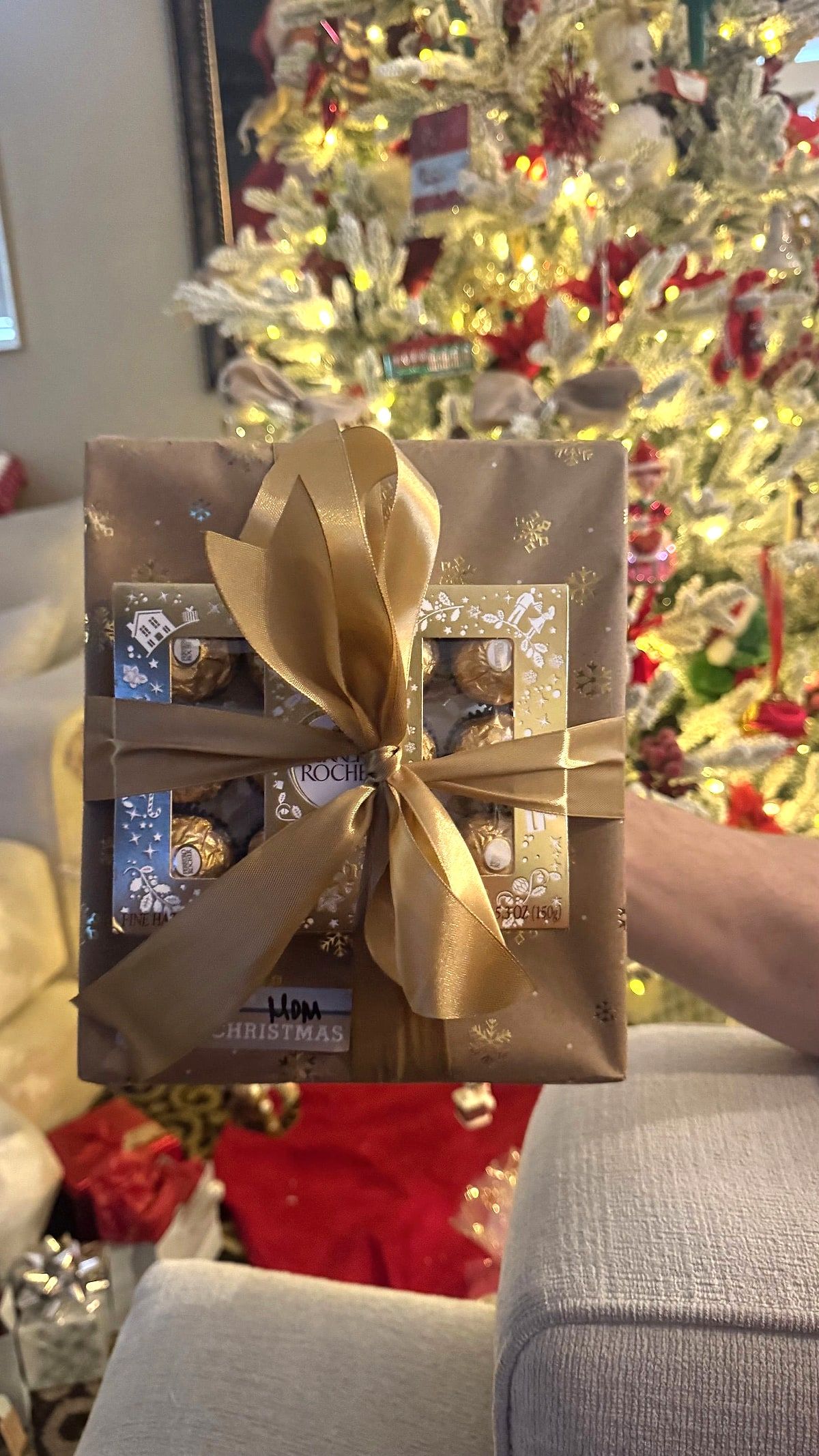 Box of chocolates wrapped in gold paper and tied with a satin gold bow
