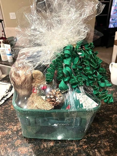 Green crate with a plush squirrel, pinecones and treats under green curly ribbon