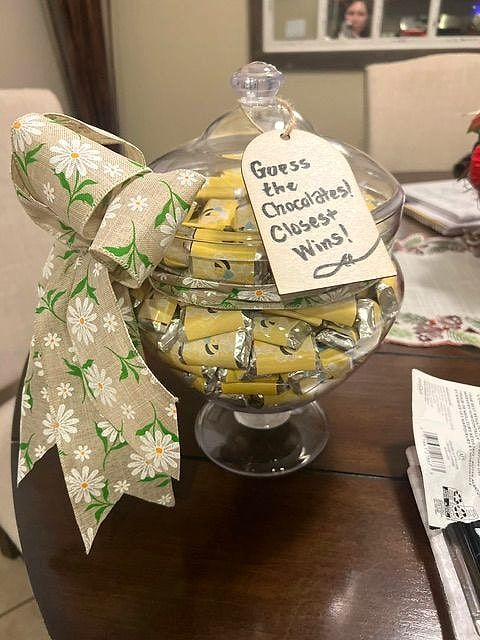 Glass candy jar full of wrapped chocolates with a 'Guess the chocolates' tag and a daisy ribbon
