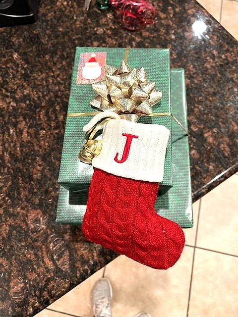 Green-wrapped gifts with a gold bow and a red knit stocking with the letter J
