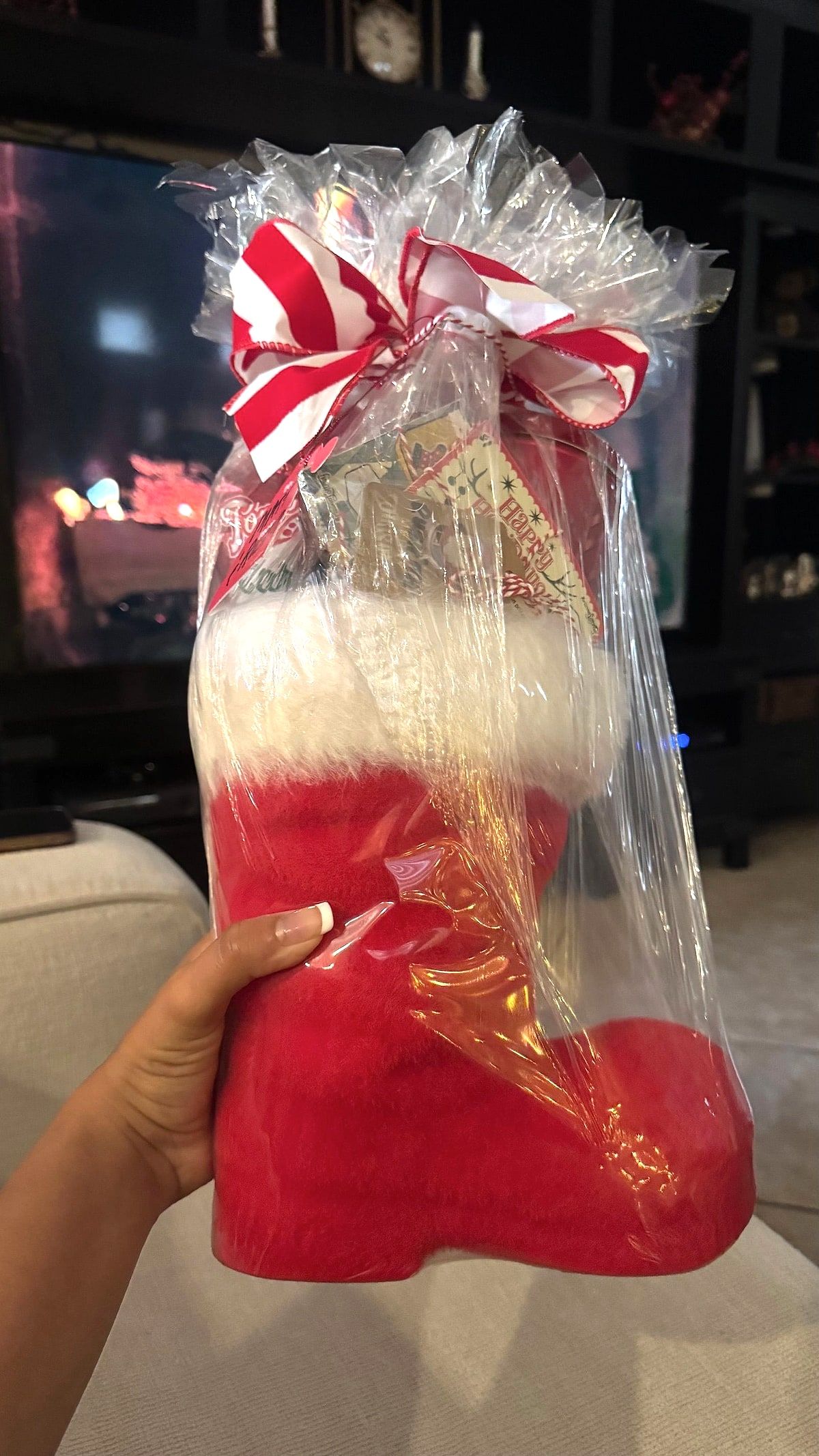 Red Santa boot filled with goodies, wrapped in cellophane and topped with a red-and-white striped bow