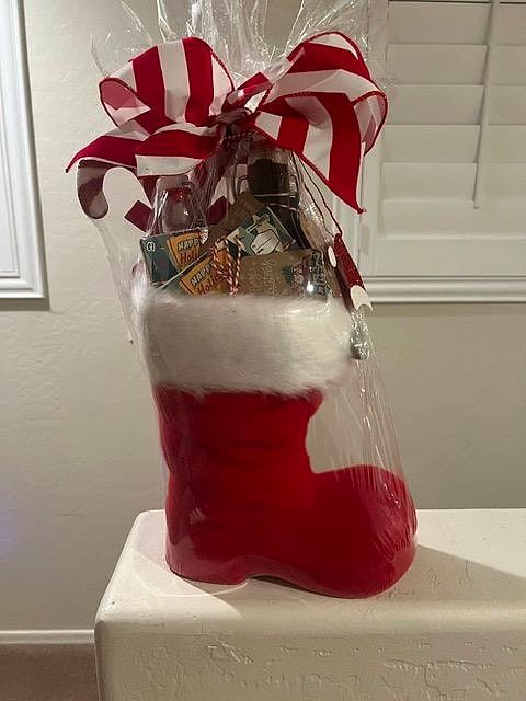 Red Santa boot with white fur trim filled with treats, topped with a red-and-white striped bow