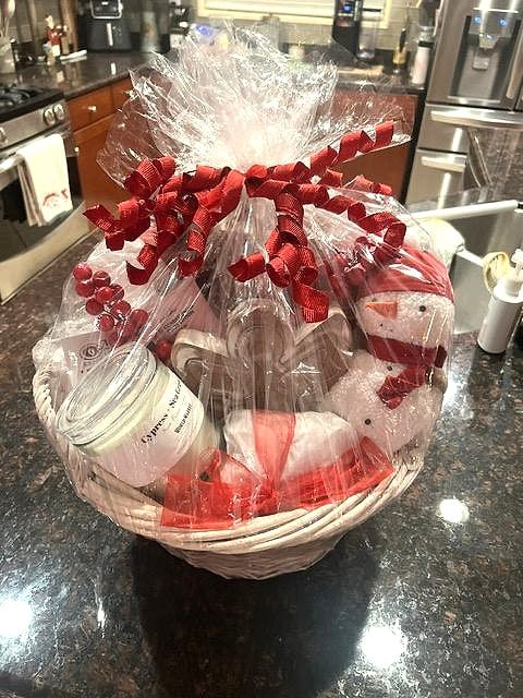 White wicker basket with a snowman, candle and treats, wrapped with red curly ribbon